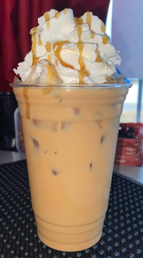 Iced caramel latte with whipped cream and caramel drizzle by the drive-thru window