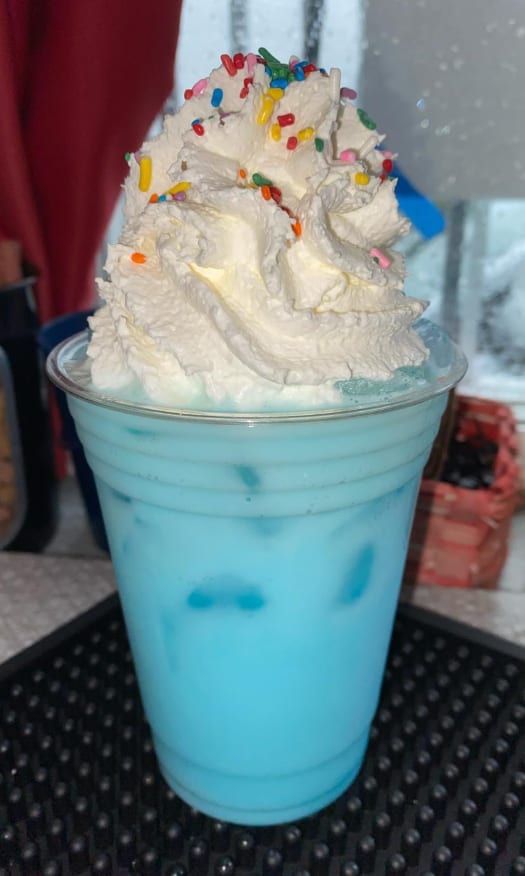 Blue energy spritzer topped with whipped cream and rainbow sprinkles