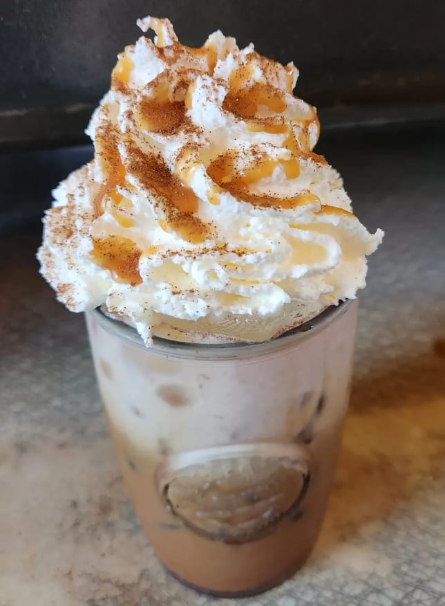 Iced mocha topped with whipped cream, cinnamon and caramel drizzle